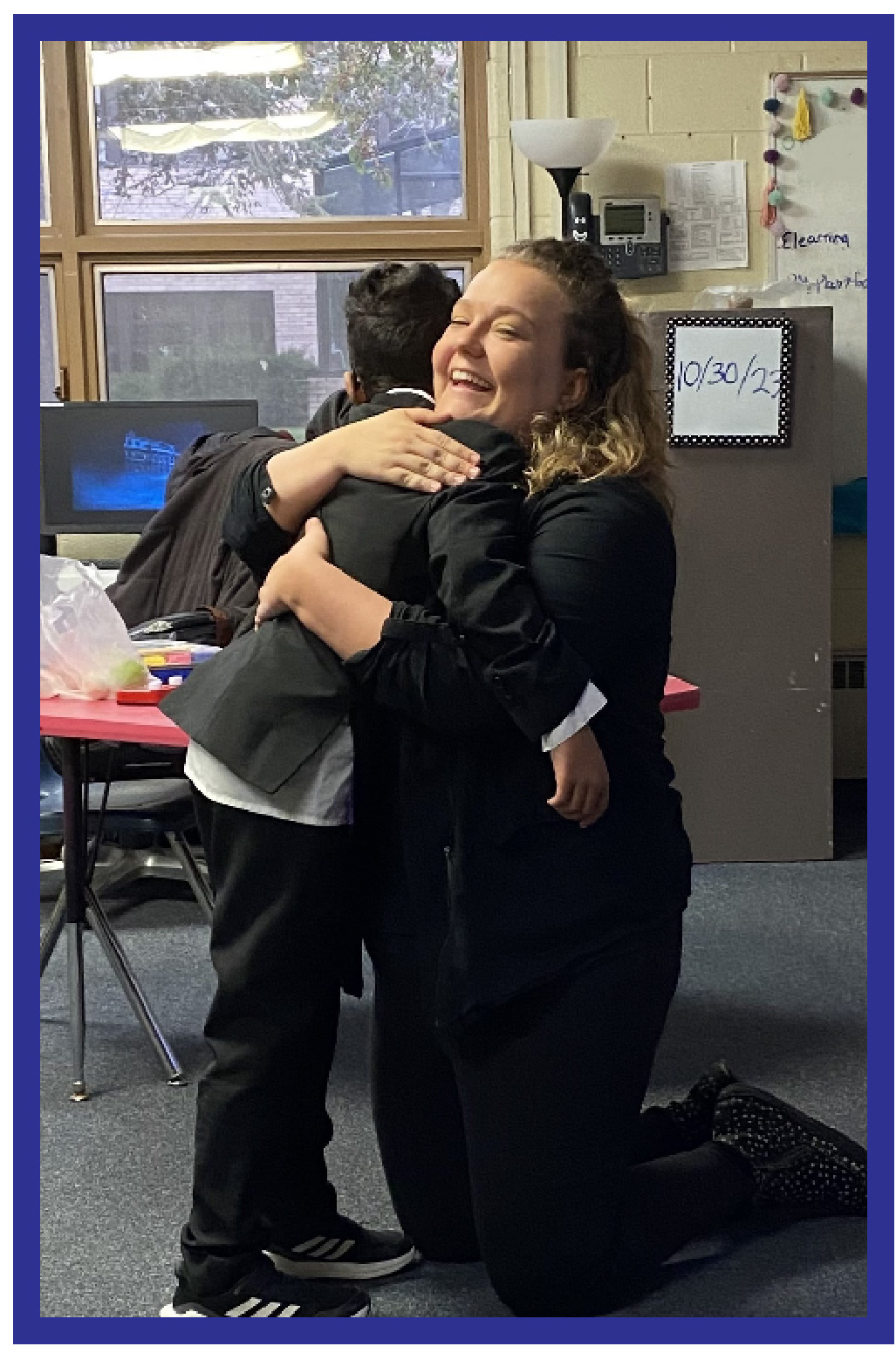 A Child and his teacher sharing a hug